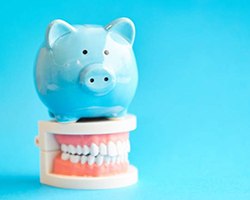 piggy bank and model teeth demonstrating cost of dental implants in Alhambra