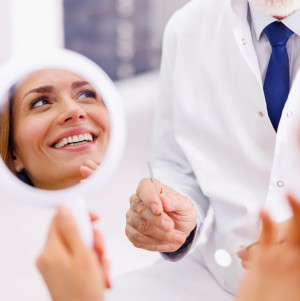 Smiling dental patient looking at her teeth in a mirror