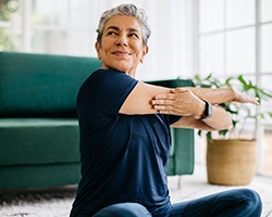 Woman smiling while stretching at home