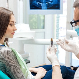 implant dentist in Alhambra showing a patient a model of a dental implant