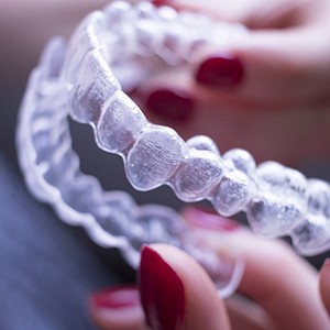 A person holding an Invisalign aligner to show its intricate details