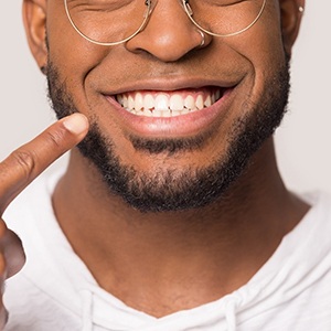 A young male with a beard and glasses pointing to his newly aligned smile