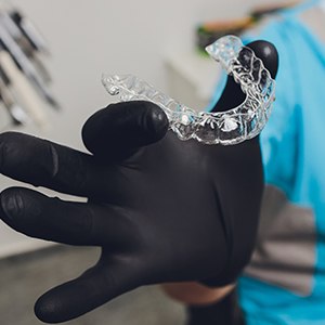 Patient using toothbrush to clean Invisalign aligner