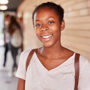teenager standing in the hall of their high school and smiling