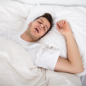 Snoring man in bed with white linens