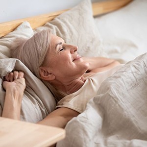 Happy, mature woman comfortable in her bed