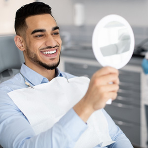 Man smiling at reflection in handheld mirror