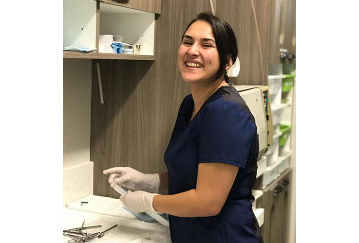 Smiling dental team member sanitizing equipment