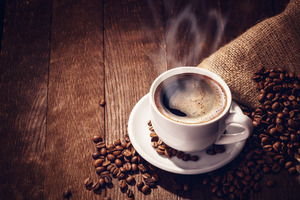 Cup of coffee surrounded by coffee beans